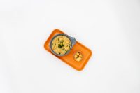 Bowl of Czech Garlic Soup Cesnecka with herb garnish and a cup of croutons on an orange tray.