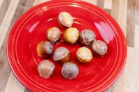 Donuts and Donut Holes Ten glazed Donut Holes, some light and some darker, piled on a red plate on a wood counter