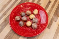 Donuts and Donut Holes Ten glazed and powdered-sugar-dusted Donut Holes piled on a red plate, from the Donuts and Donut Holes recipe.