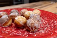 Donuts and Donut Holes Glazed Donut Holes dusted with powdered sugar piled on a red plate