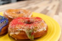 Donuts and Donut Holes Glazed Donuts and Donut Holes on a yellow plate, one topped with red and green sugar sprinkles.