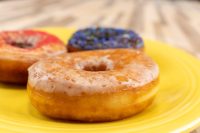 Donuts and Donut Holes Three glazed Donuts and Donut Holes on a yellow plate, topped with red glaze and dark sprinkles.
