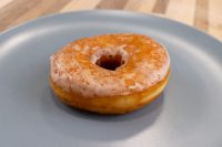 Donuts and Donut Holes A single glazed ring donut from a Donuts and Donut Holes recipe, resting on a grey plate.