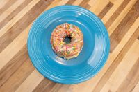 Donuts and Donut Holes A glazed ring donut with rainbow sprinkles from the Donuts and Donut Holes recipe, on a blue plate.