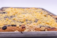 Sheet Kolach with Streusel Sheet Kolach with Streusel in a metal pan, golden streusel crumbs covering dark berry filling at the edges.