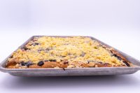 Sheet Kolach with Streusel Side view of Sheet Kolach with Streusel in a metal baking sheet, streusel crumbs and dark berry filling visible.