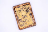 Sheet Kolach with Streusel Overhead view of baked Sheet Kolach with Streusel, golden crumb topping over dark berry filling in a metal pan