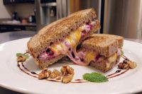 Halved Grilled Cheese with Goat Cheese and Beets, oozing melted cheese and purple filling, plated with walnuts and mint.