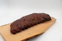 Whole rack of American BBQ – Honey Pork Ribs with a dark caramelized crust on a wooden board.