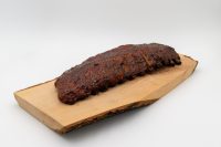 A dark, glazed rack of American BBQ – Honey Pork Ribs resting on a bark-edged wooden board.