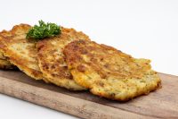 Side Potato Pancakes Bramboráčky Four golden-brown Side Potato Pancakes Bramboráčky fanned on a wooden board with a parsley sprig.