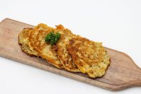 Side Potato Pancakes Bramboráčky Four golden-fried Side Potato Pancakes Bramboráčky on a wooden board, garnished with a sprig of dill.