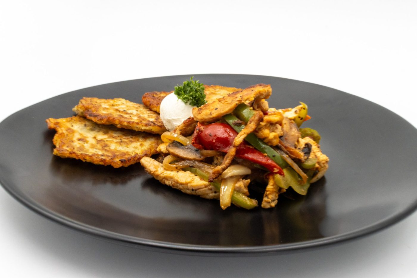 Slovak Meat Sauté Mäsové Soté with peppers and onions, sour cream and parsley, served with potato patties