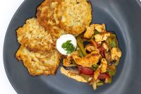 Potato pancakes beside Slovak Meat Sauté Mäsové Soté with sour cream and parsley on a grey plate