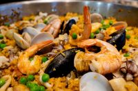 Close-up of Paella with saffron rice, shrimp, mussels, clams, and peas in a metal pan
