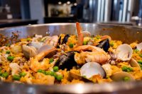 Close-up of a paella pan with saffron rice, shrimp, mussels, clams, and green peas.