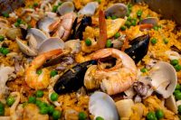 Close-up of Paella with shrimp, mussels, clams, and peas in saffron rice.
